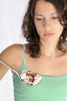Shot of cute girl with spoon full of pills. Concept shot for alternative medicine