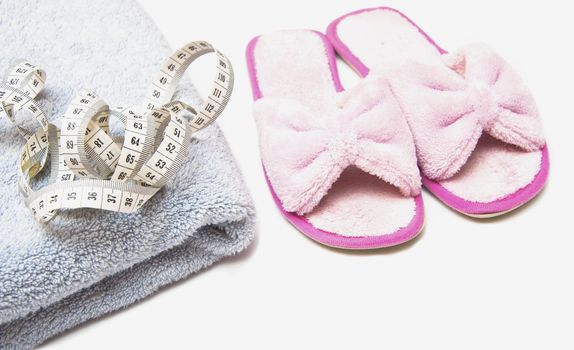 slippers, grey folded towel and metr on white