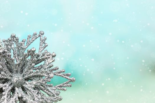 Silver snowflake ornament against a blue background with copyspace. Shallow DOF.