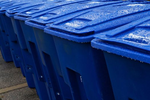 Close up of wet blue large recyling bins