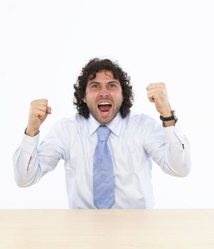 Happy businessman raising his arms sitting at his desk isolated on white background