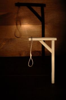 Gibbet with loop on gloomy wooden background