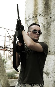 Soldier in camouflage and glasses with the gun up