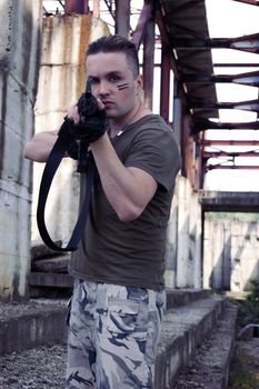 Man in camouflage with gun over metalic construction