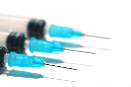 three hypodermic needles and syringes on white