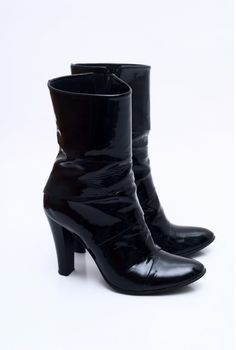 Black shine patent woman leather boots with a heel isolated over white