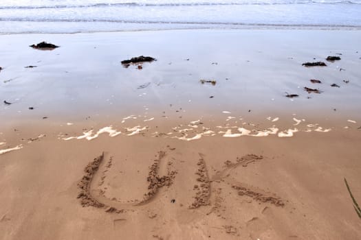 uk inscribed on the beach with ocean waves in the background