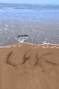 uk inscribed on the beach with ocean waves in the background