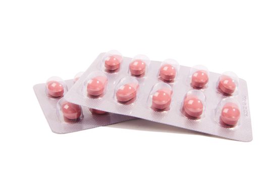 Lot pink pills over white background
