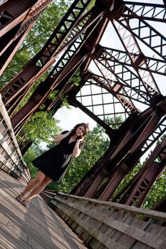 A carefree brunette woman walking along an old rusted bridge.