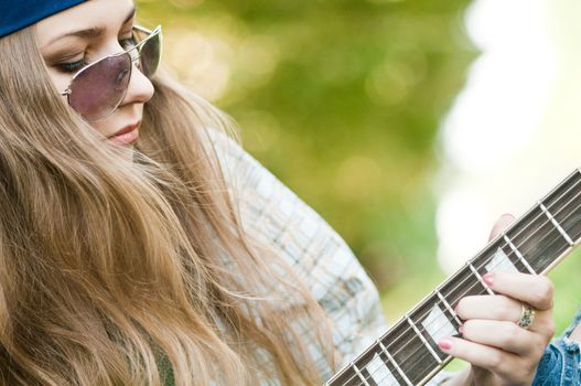 Rocking girl on a nature with guitar