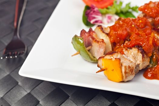 shashlik on a plate with a tomato and salad leaf