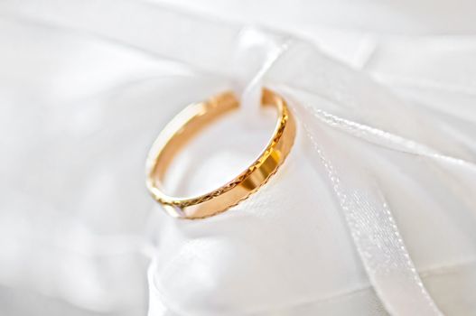 Classic gold wedding ring on white satiny fabric
