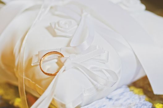 Classic gold wedding ring on white satiny fabric