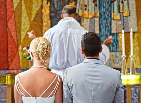 Newlyweds in a church listening to a priest