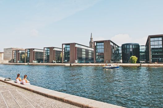 City river with tourist boat and modern buildings on the riverside