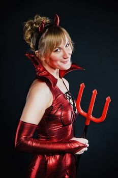 Red devil woman with trident on black background