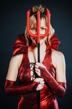 Red devil woman with trident on black background