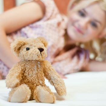 Beautiful young girl with bear toy in bed