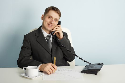 Smiling businessman in talks on the phone in the office