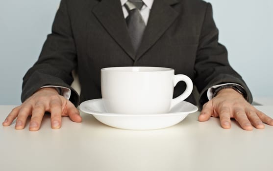 A huge cup of coffee on the table near the businessman