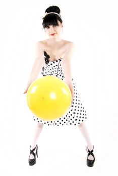 Portrait of a young beautiful brunette posing with yellow ball