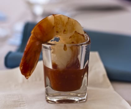 a large shrimp cocktail in a shot glass on a napkin