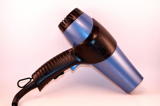 Blue hairdryer on soft background. Cosmetic appliance for beauty and fashion.