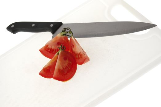 Cutting white plastic board with a knife and tomato isolated on a white background.