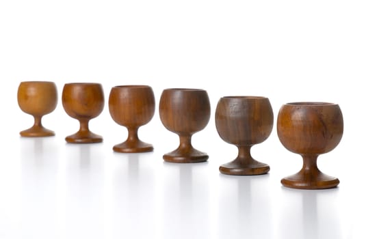 Wooden cups aligned isolated on white background.