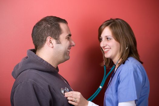 A young doctor or nurse listening to the heartbeat of her patient with her stethoscope during an office visit.