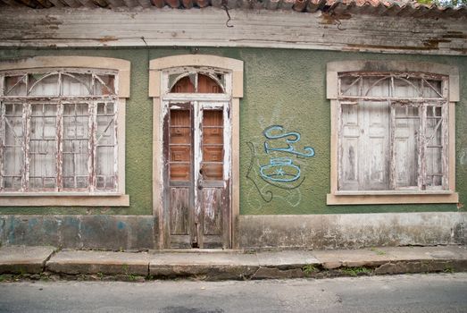 Old house facade with broken door and windows.