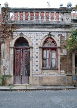 Old house facade with broken door and windows.