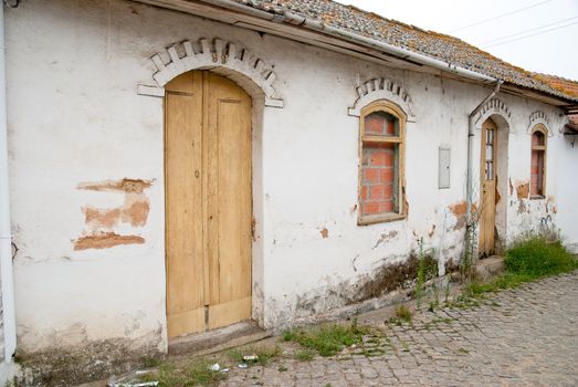 Old house facade with broken door and windows.