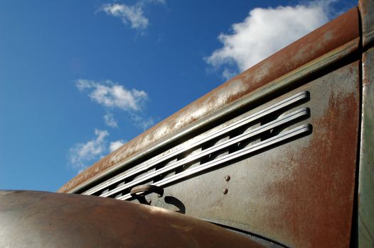 rusting 1950's pick-up truck against blue cloudy sky