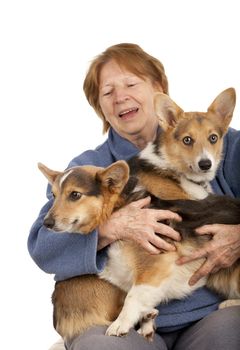 senior woman holding two active corgi puppies on her laps