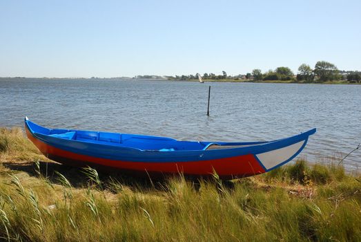 Colorful fishing boat on green grass on a sunny day with clear blue sky.