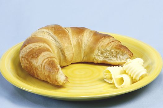 Croissant with butter over light blue background