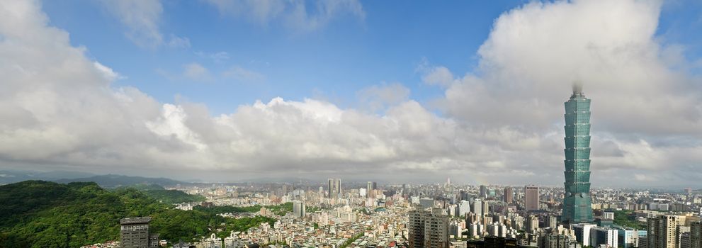 Taipei city skyline with famous 101 skyscraper building under white clouds and blue sky in Taiwan. Horizontal panoramic cityscape.