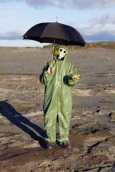 The person in protective clothes with an umbrella waits a radioactive rain