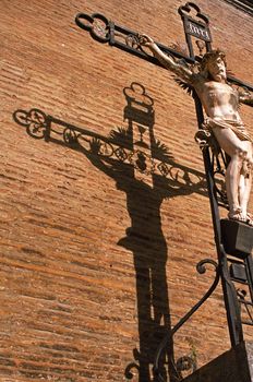 Crucifixion silhouetted on the wall of Eauze cathedral in SW France