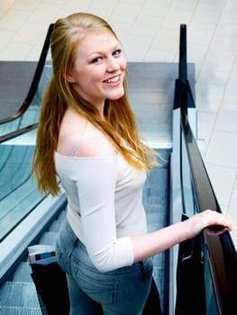 Smiling young shopper riding on escalator