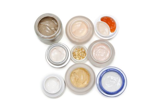 Opened banks with make-up cream on white background