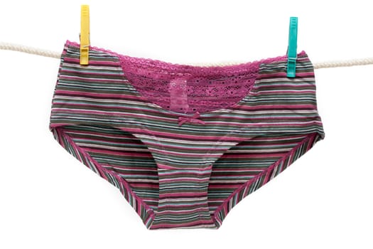 Feminine lacy panties hung on linen rope with multicolored clothes-peg