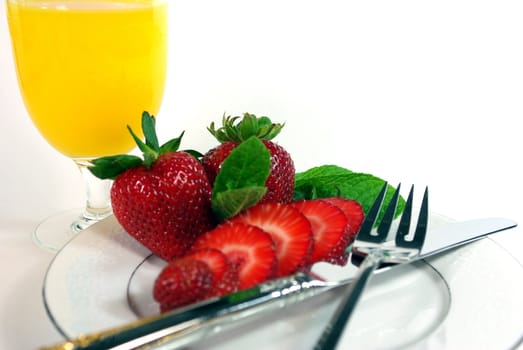 Sliced strawberries and orange juice on a white background