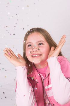 Cute blond girl throwing confetti in the air and watching it come down