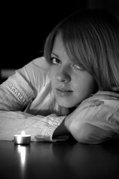 Lonely girl with lit candle in black and white