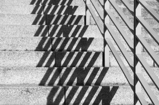 A banister's shadow is falling on the steps of an outside stair. High contrast black & white. Note: shallow depth of field.
