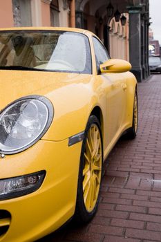 The wet yellow car in city street