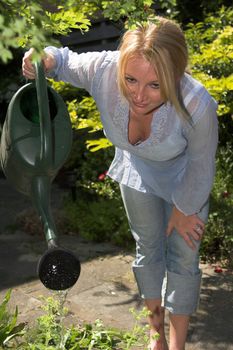 Pretty blond woman watering the plants